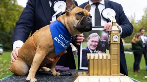 PA Media Vivienne, winner of Westminster Dog of the Year, with photo of owner Sir David