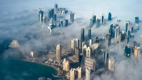 EPA An aerial view of high-rise buildings emerging through fog in Doha, Qatar (15 February 2014)