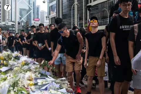 Getty Images A queue of people dressed in black lay flowers at this site on a busy Hong Kong street