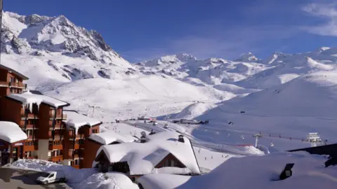 Mountains covered by snow with the buildings and ski lifts of a ski resort in the foreground