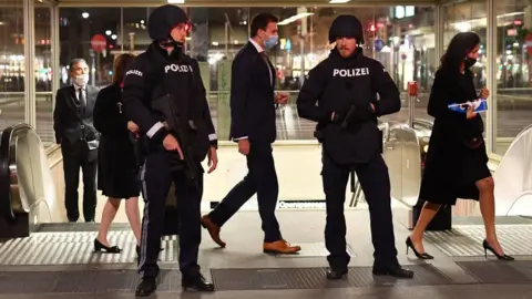 Getty Images Opera guests walk past policemen after leaving the state opera in Vienna