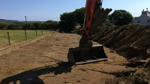 Manx Utilities Digger excavating trench