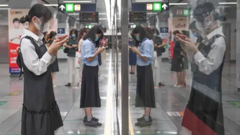Getty Images Passengers looking at their smartphones in a subway station in China