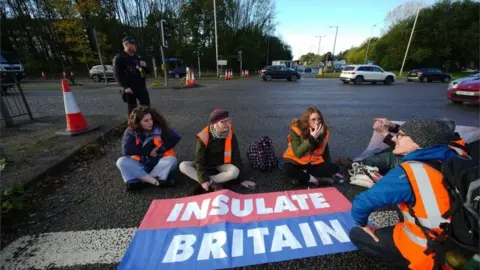 PA Media Protesters from Insulate Britain blocking a road near Manchester Airport