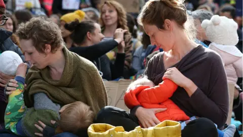 PA Media Parents breastfeed their ne borns during a "nuse-in"