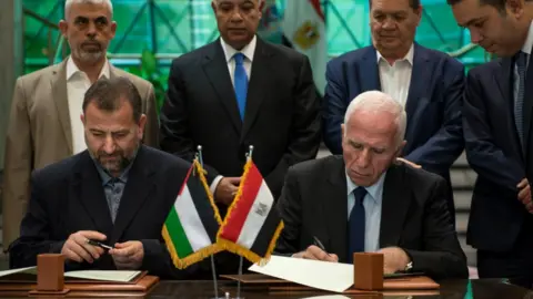 EPA Palestinian member of Fatah Central Committee, Azam al-Ahmed (right), and Hamas deputy head of the politburo Saleh al-Aruri sign an agreement between the two Palestinian factions in Cairo, Egypt, 12 October 2017