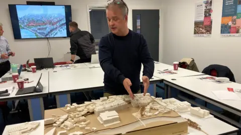 Architect Ben Sykes shows a model of the redevelopment plan.