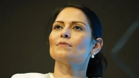 A woman smirking, she is looking above the camera.