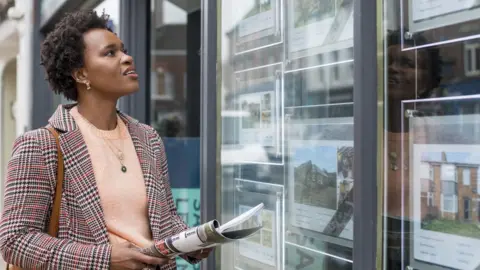 Getty Images Woman looking in estate agent's window