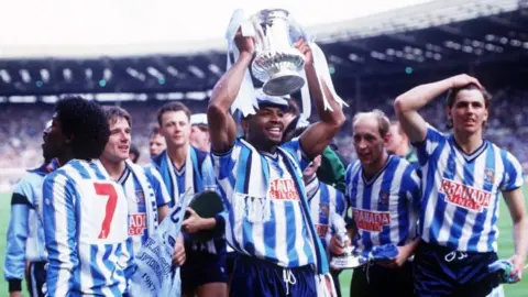 Getty Images Regis holding the FA cup in 1987 surrounded by his team mates