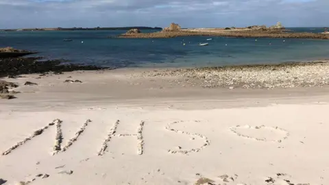 John Peacock "NHS" drawn on beach