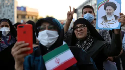 Reuters Supporters of Ebrahim Raisi hold a photo of him at a rally in Tehran, Iran, following his presidential election victory (19 June 2021)