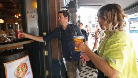 PA Media Punters collecting takeaway pints at the pub