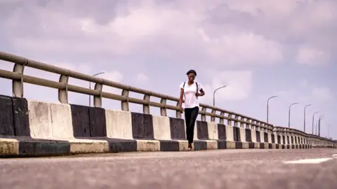 BBC/Ayo Bello A woman walking on the Third Mainland Bridge in Lagos, Nigeria