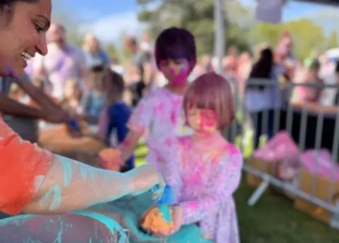 Jon Wright/BBC A small girl is handed some coloured paint powder