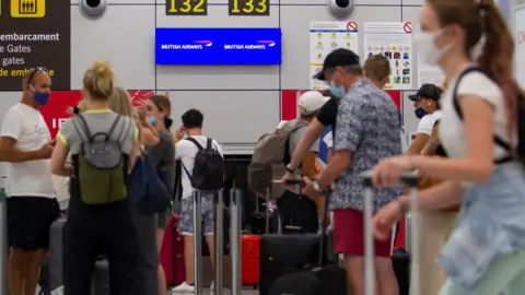 Getty Images Passengers check-in for flights back to the UK at an airport in Mallorca