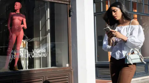 Getty Images Woman walks past shop