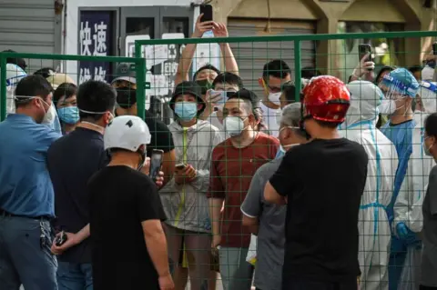 Getty Images Angry residents confront officials from behind a fence erected in a neighbourhood compound in the Xuhui district of Shanghai on June 6, 2022.