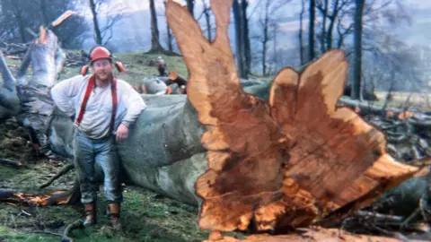 Walter Renwick A colour photo from some time ago shows Walter Renwick wearing jeans, red braces and a white shirt standing next to a large tree which has just been felled.