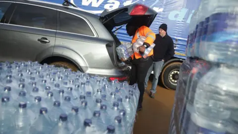 Yui Mok/PA WIRE Water bottles loaded into car