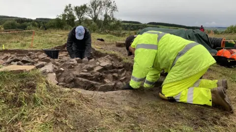 Volunteers excavate around an area where a spiral staircase is believed to have been located.