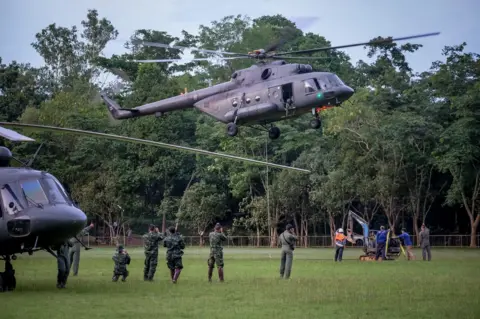 Getty Images Helicopter from Thai air force carry a mini excavator to the mountain top where they are trying to make a hole to get into Tham Luang Nang Non cave