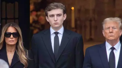 Reuters Barron Trump stands alongside his mother Melania and father Donald