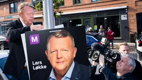 MARTIN SYLVEST/EPA-EFE/REX/Shutterstock Chairman of the Moderates Lars Lokke Rasmussen (C) puts up election posters and offers muffins, coffee and a chat on the main street in Haslev, Denmark, 08 October 2022