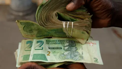 Reuters A vendor in Harare with new old $2 bond notes and new $2 Zimbabwean notes in November - Zimbabwe
