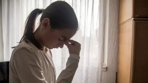 Getty Images/ljubaphoto Girl with head in hands