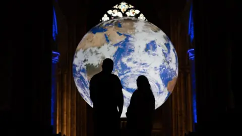 Durham Cathedral Visitors silhouetted against the illuminated globe of earth