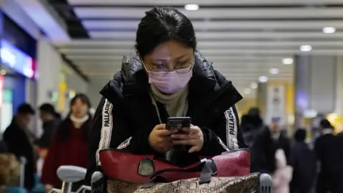 EPA A passenger arrives wearing a mask at Terminal 4, Heathrow Airport, London