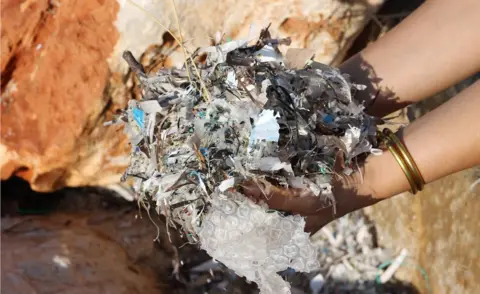 Washed-up plastic gathering between rocks on Paros