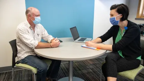 Getty Images Therapist seeing patient, both wearing masks