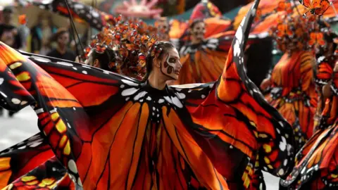 Getty Images Women dressed as butterflies dance during the parade