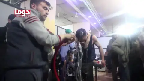 AFP Photo/ HO/ Douma City Co-Ordination Committee man pouring water over the head of another man (still from video)