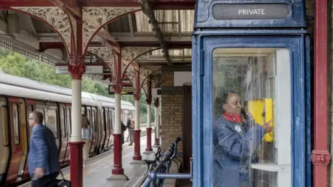 Historic England A platform attendant checks for a good line at Chorleywood station on the Metropolitan Line