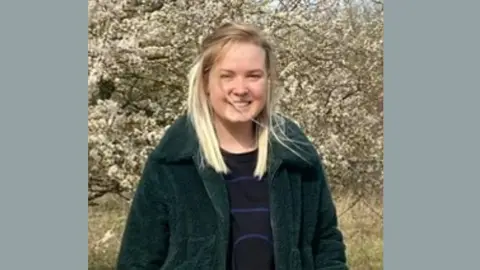 Family photo Lily Lucas smiling at the camera as she stands outside on a sunny day