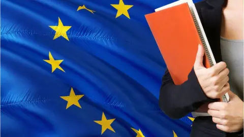 Getty Images Young woman standing with the European Union flag in the background.