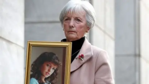 PA Media A picture of Marie McCourt holding a picture of her daughter