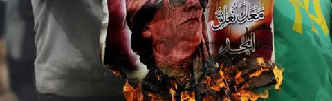 AFP Man holding a burning poster of Muammar Gadaffi