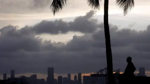 Reuters A silhouette of a man and a palm tree with Miami skyline and clouds behind him