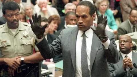 Getty Images OJ Simpson shows the jury a pairs of gloves he was asked to wear during the trial