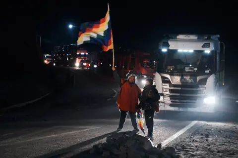 NATALIA FAVRE A man waves the flag of the indigenous communities (Wiphala), while giving way to vehicles during the roadblock in Purmamarca, Jujuy province, Argentina, June 22, 2023.