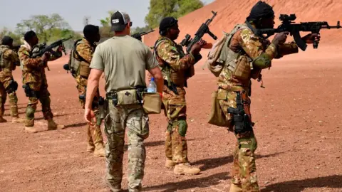 A US army instructor walks next to Malian soldiers on April 12, 2018 during an anti-terrorism exercise at the Kamboinse.