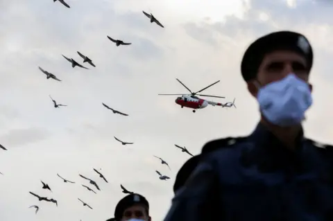 Reuters A police helicopter is seen flying over police officials wearing face masks.