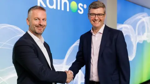 Kainos Russell Sloan and Brendan Mooney shaking hands in the Kainos boardroom