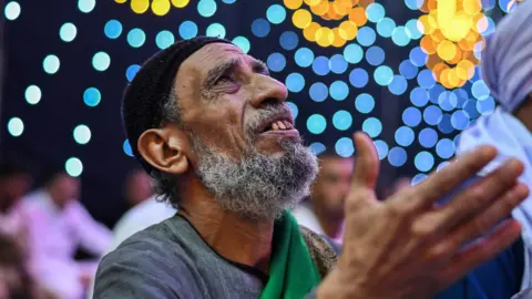 An image of a man praying with bright lights behind him in Egypt