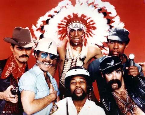 Michael Ochs Archives / Getty Images The Village People pose in a group studio shot wearing their various costumes against a red background, taken in 1977.