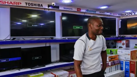 EPA A Kenyan electronics dealer stands by blank screens that should be playing the three suspended channels